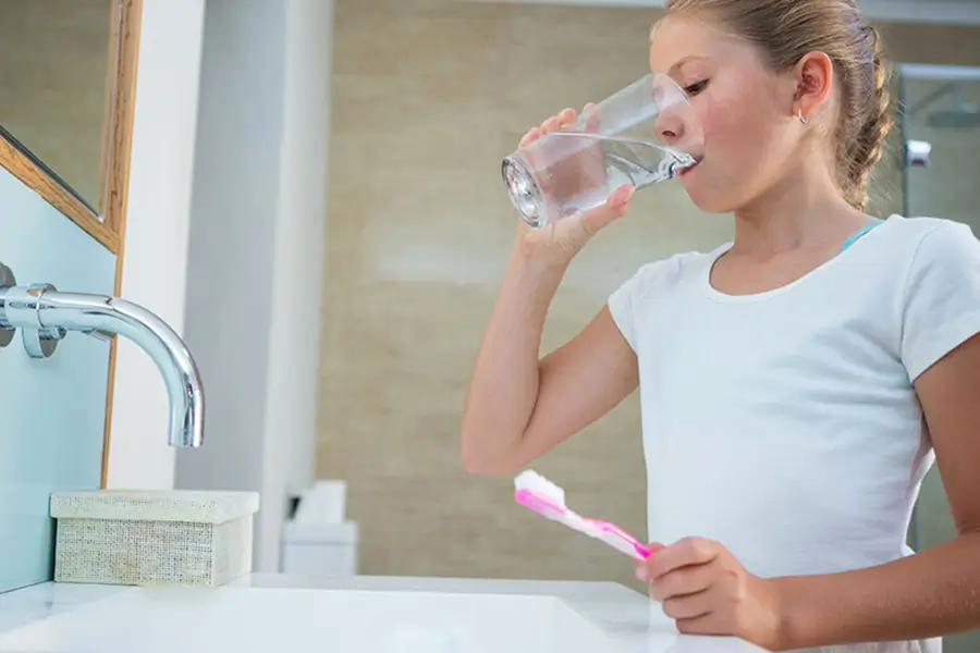 girl drinking water while brushing teeth instead of wasting water